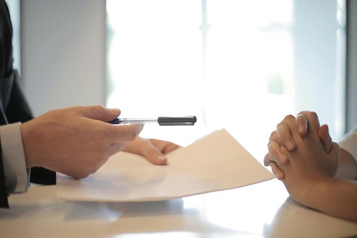 A person signing paperwork at a desk to start reporting rent payments